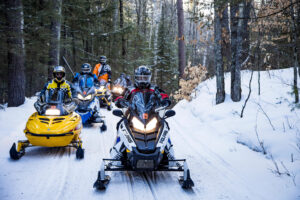 A group of people snowmobiling in the woods